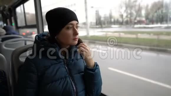 一个成年东方女孩坐着望着一辆穿过城市的公共汽车的窗外窗外视频的预览图