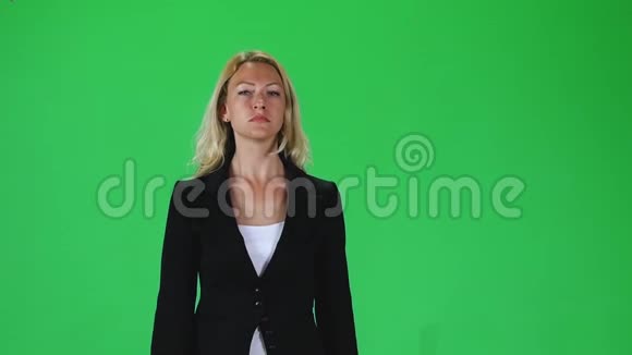 穿着黑色夹克的金发女孩对着绿色的屏幕直视着相机慢动作视频的预览图