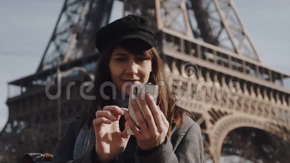微笑着年轻的欧洲旅游妇女使用智能手机社交网络应用程序在著名的巴黎埃菲尔铁塔慢动作视频的预览图