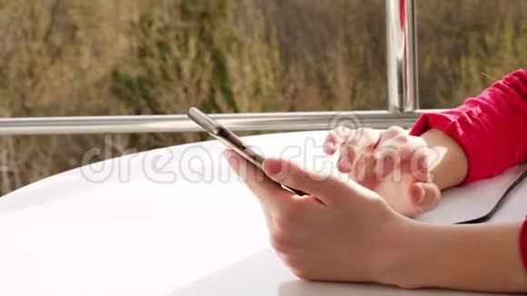 特写双手少年少女使用智能手机在开放式阳台上春天阳光明媚的一天视频的预览图