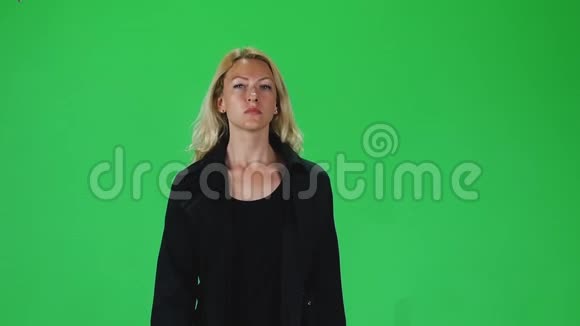 穿着黑色外套的金发女孩在绿色屏幕上直视着相机慢动作视频的预览图