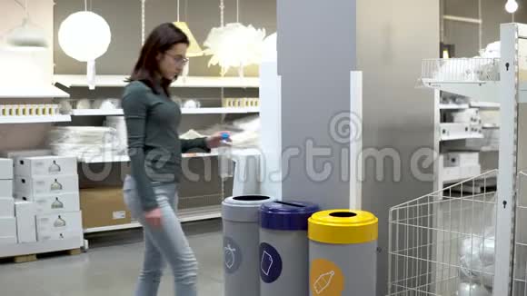 一个年轻的女人把一个塑料瓶扔进垃圾桶垃圾分类专用容器塑料容器视频的预览图