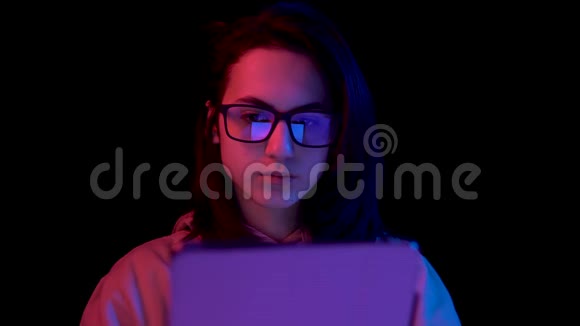 带着药片的年轻女人一个女人在用平板电脑蓝色和红色的光落在黑色背景上的女人身上视频的预览图