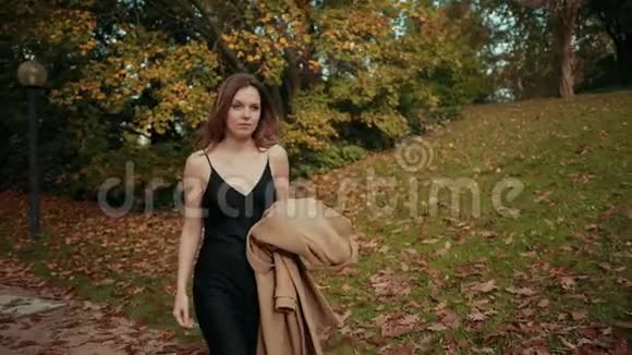 女人走过一个秋天的公园冷的把棕色的外套放在身上保暖视频的预览图