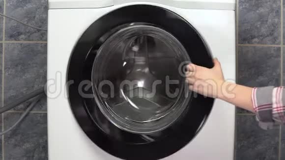 一位年轻妇女正积极地用洗衣机装衣服女人打开洗衣机扔衣服视频的预览图