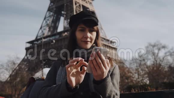 美丽的年轻白种人自由职业者使用智能手机购物应用程序下阳光巴黎埃菲尔铁塔慢动作视频的预览图
