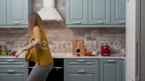 20岁的孕妇妈妈在厨房里跳舞和听音乐视频的预览图