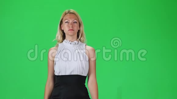金发女孩穿着黑白连衣裙对着绿色的屏幕直视着相机慢动作视频的预览图