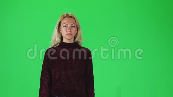 金发女孩穿着石榴毛衣对着绿色的屏幕直视着相机慢动作视频的预览图