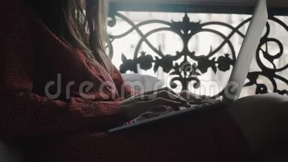 在舒适的法国阳台床上用笔记本电脑拍摄快乐美丽的女商人的电影特写视频的预览图