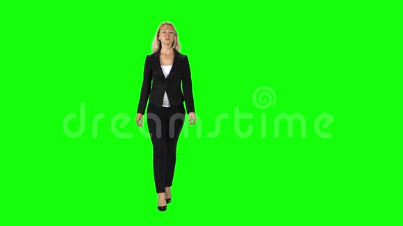 金发女孩穿着黑色西装白色衬衫和高跟鞋穿着绿色的屏幕视频的预览图