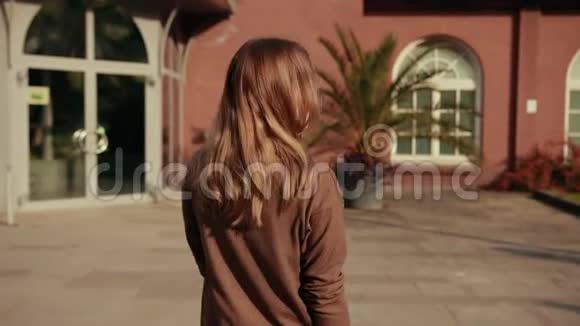 女人棕色头发棕色毛衣从镜头前走开扭来扭去微笑着视频的预览图