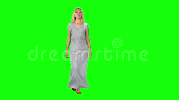 一个穿着灰色长裙的金发女孩在绿色屏幕上直视镜头视频的预览图
