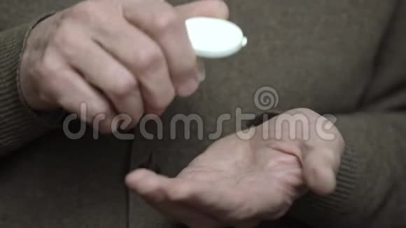 老人把白色药丸从瓶子的近处倒在手掌上视频的预览图