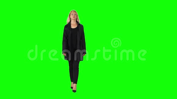 金发女孩穿着黑色外套裤子和高跟鞋穿着绿色的屏幕视频的预览图