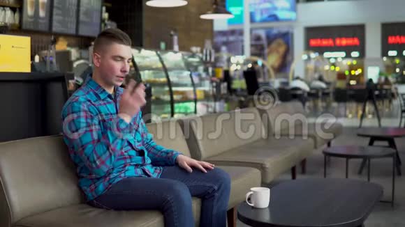 一个年轻人坐在咖啡馆里打电话一个男人正在打电话喝咖啡特写镜头视频的预览图