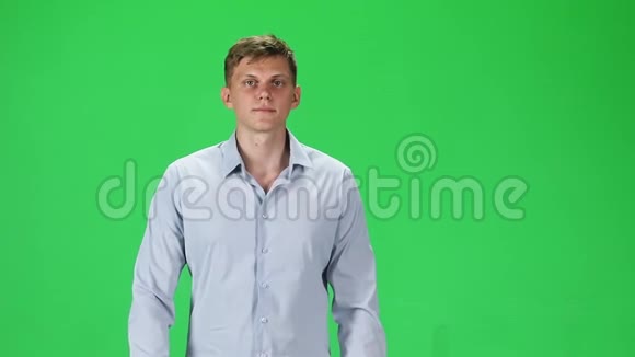 穿着灰色衬衫的年轻人在绿色背景下向前看慢动作视频的预览图