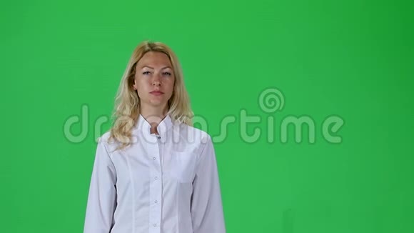 金发女孩穿着白色的医疗外套对着绿色的屏幕直视着相机慢动作视频的预览图