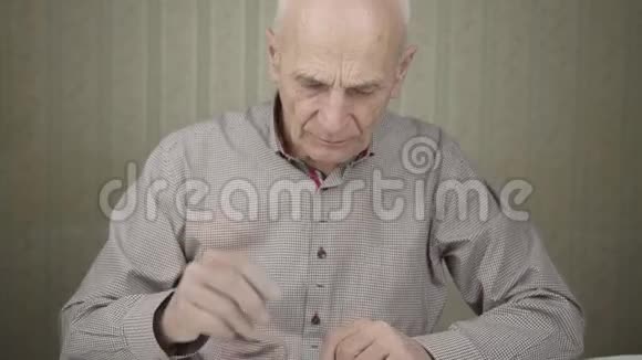 穿灰色衬衫的老人吃药喝水视频的预览图