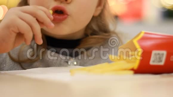 小女孩在咖啡馆里吃快餐炸薯条肖像特写视频的预览图