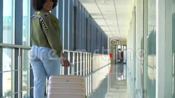 非裔美国女旅客正提着行李在候机厅后向外移动视频的预览图