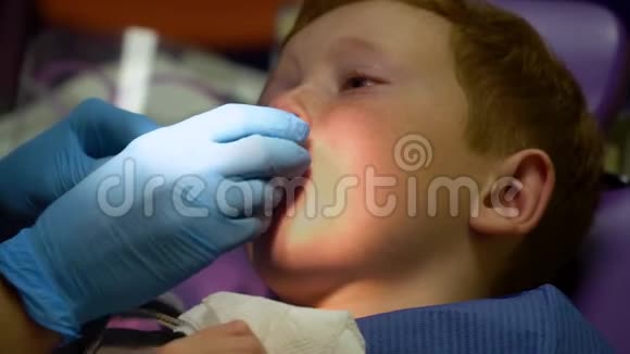 害怕的红发男孩在牙科椅上接待牙医时哭泣儿科牙医视频的预览图