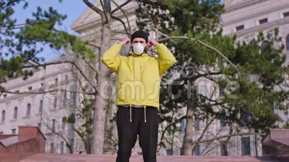 一个穿着黄色夹克的学生他站在空荡荡的街道中间把防护面具戴在脸上视频的预览图