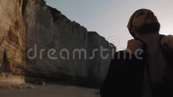 电影拍摄的快乐微笑的游客男子观看巨大的阳光岩石悬崖诺曼底海滩附近的埃特雷塔慢动作视频的预览图