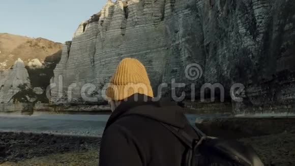镜头绕着快乐的男性游客探索史诗般的阳光岩石海滩在Etretat慢动作中寻找灵感视频的预览图