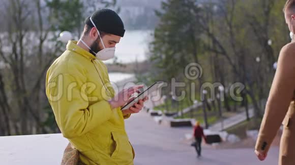 新的Covid19概念在公园的中间一个穿着黄色夹克的人用平板胶带贴着他的东西视频的预览图