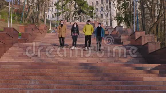 在镜头前一群朋友从公园的楼梯上下来他们戴着防护面具聊天视频的预览图