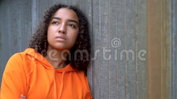 在城市环境中穿着橙色连帽衫的非洲裔美国少女少女看起来很悲伤视频的预览图