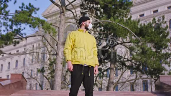 穿着一件黄色夹克一个人站在空街中央的摄像机前穿着隔离衣视频的预览图