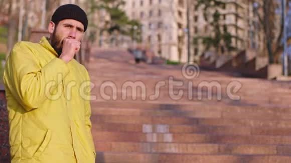 一个穿着黄色夹克的人在公园外面咳嗽没有面具有人给他面具他很高兴带着面具视频的预览图