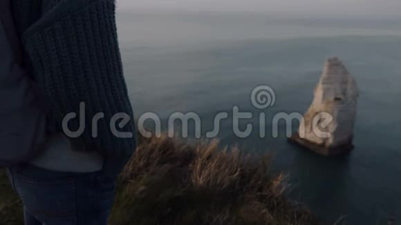美丽体贴的旅游妇女看着美丽的日落全景在埃特雷特海边悬崖诺曼底慢动作视频的预览图