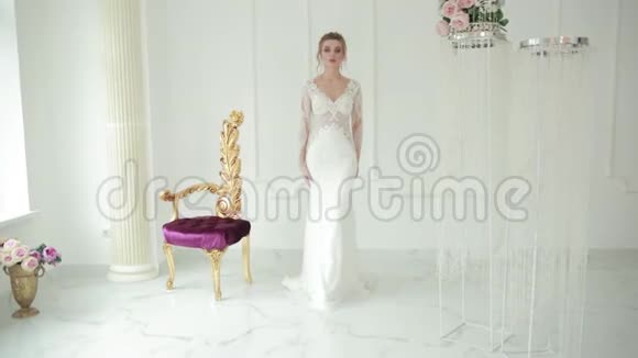 金发新娘穿着白色美人鱼风格的婚纱向前走触摸着礼服视频的预览图