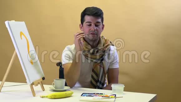 一位艺术家坐在桌子旁等待缪斯画一幅画视频的预览图