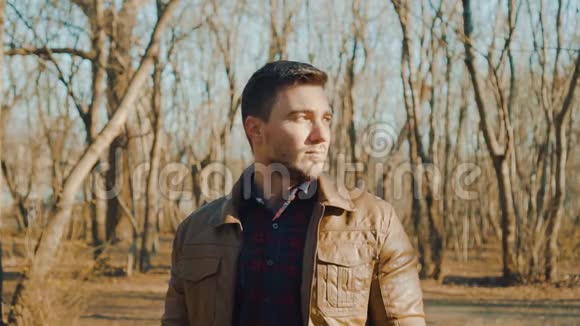 春天或秋天公园背景上穿皮夹克的人的肖像一个严肃的家伙正在调查视频的预览图