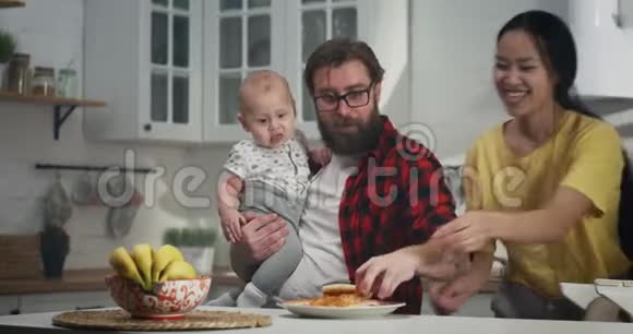 年轻夫妇和他们的孩子一起吃早餐视频的预览图