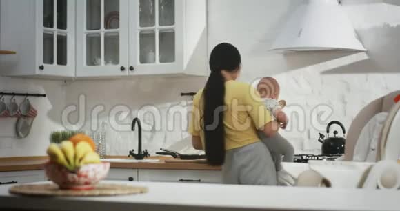 年轻的妈妈抱着孩子做家务视频的预览图