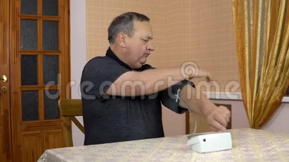 男人用一个装置来测量心脏压力一位老人把血压监测仪放在手上测量视频的预览图