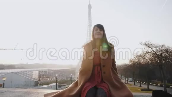 肖像美丽幸福微笑的旅游女子坐着举手在日出巴黎埃菲尔铁塔观景慢动作视频的预览图
