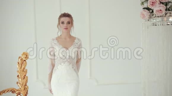 年轻的金发新娘穿着白色婚纱摆着相机旋转视频的预览图