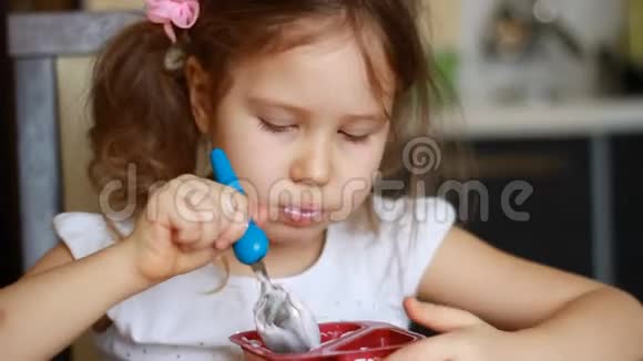 可爱的女婴在厨房里吃奶酪儿童早餐吃酸奶的肖像视频的预览图