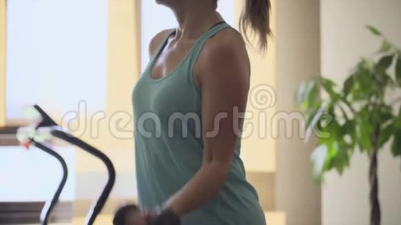 运动的年轻女子独自在客厅里用哑铃做运动穿运动装的女孩在家里训练身体健康视频的预览图