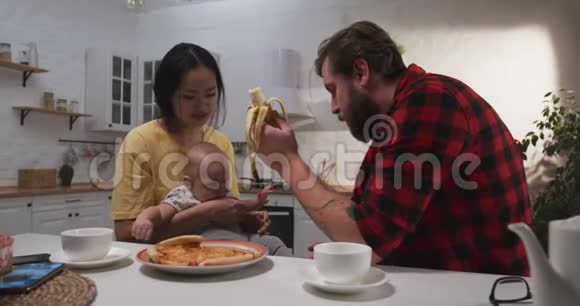 年轻夫妇和他们的孩子一起吃早餐视频的预览图
