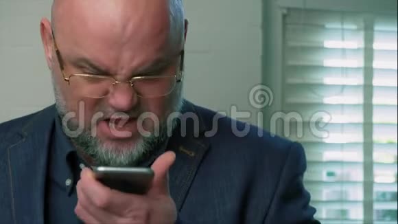 愤怒的情绪激动的男人对着对话者在智能手机上交谈视频的预览图