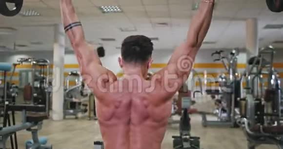 从一个健美男子的背部拍摄视频他在现代健身房锻炼背部以获得更多的肌肉视频的预览图