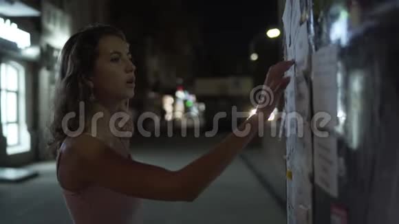 美丽的年轻女孩看贴在街道上的广告视频的预览图