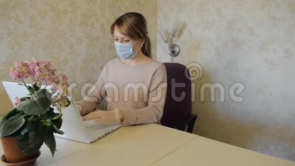 戴防护面罩和手套的年轻女子在笔记本上做笔记在电脑上工作视频的预览图